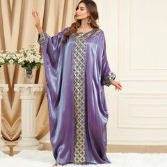 استمتعي بالجاذبية المتلألئة للجلابية الحريرية، التي تنضح بحس فني تتميز بأكمام فضفاضة تشبه جناح الخفاش، ورقعة جاكار معقدة