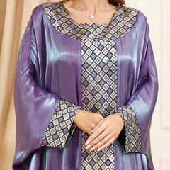 استمتعي بالجاذبية المتلألئة للجلابية الحريرية، التي تنضح بحس فني تتميز بأكمام فضفاضة تشبه جناح الخفاش، ورقعة جاكار معقدة