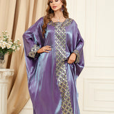 استمتعي بالجاذبية المتلألئة للجلابية الحريرية، التي تنضح بحس فني تتميز بأكمام فضفاضة تشبه جناح الخفاش، ورقعة جاكار معقدة