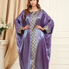 استمتعي بالجاذبية المتلألئة للجلابية الحريرية، التي تنضح بحس فني تتميز بأكمام فضفاضة تشبه جناح الخفاش، ورقعة جاكار معقدة