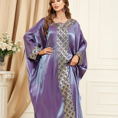 استمتعي بالجاذبية المتلألئة للجلابية الحريرية، التي تنضح بحس فني تتميز بأكمام فضفاضة تشبه جناح الخفاش، ورقعة جاكار معقدة